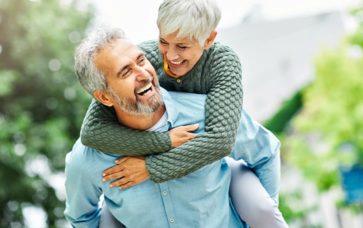 Ein älteres Paar, wobei der Mann die Frau auf dem Rücken trägt