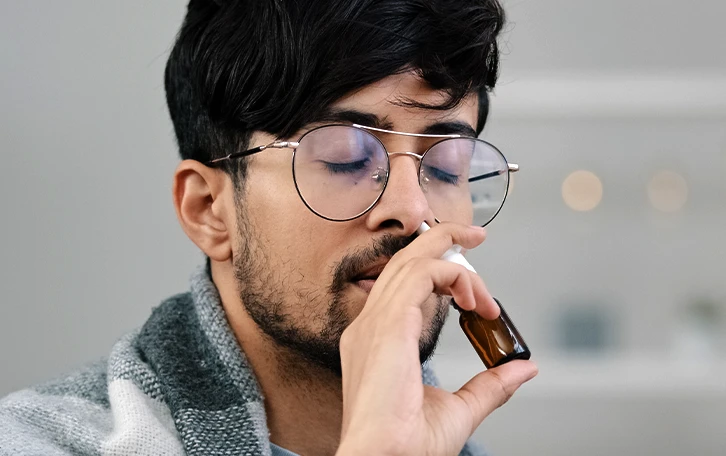 Eine männliche Person verabreicht sich ein Nasenspray